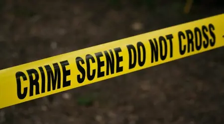Een gele lint met de engelse tekst in zwarte letters: crime scene do not cross