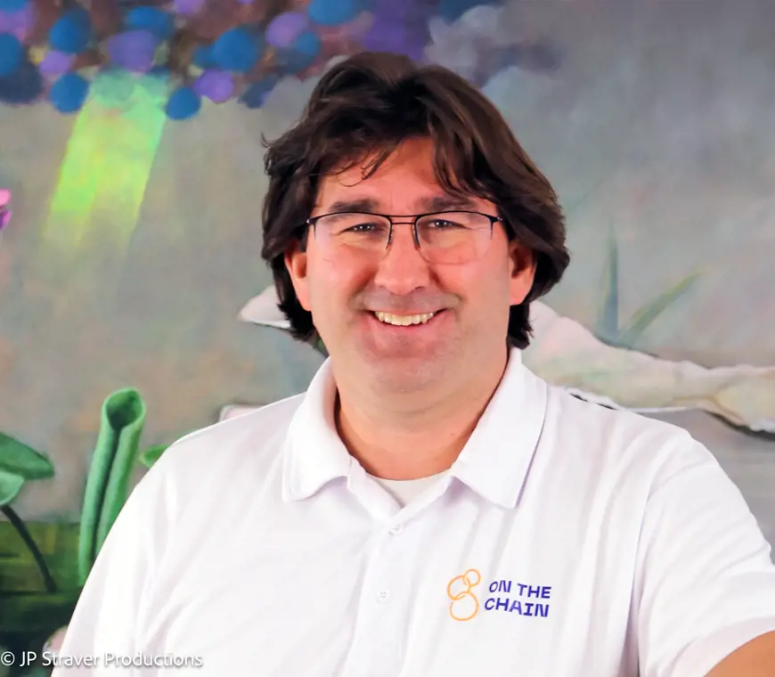 Een portret foto van John-Paul Straver in een witte polo met de logo van On The Chain op zijn borst.