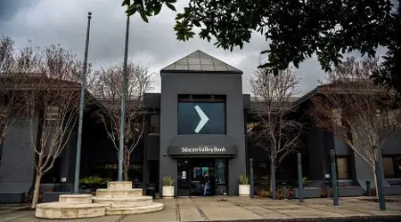 Hoofdkantoor van Silicon Valley Bank met moderne architectuur, omgeven door kale bomen en een bewolkte lucht.