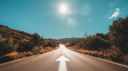 Een foto van een snelweg met een lange witte pijl die naar de verte wijst op de weg.